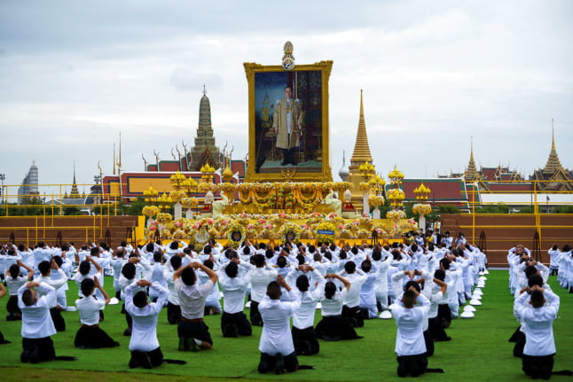 People pay their respects to a picture of Thailand's late King Bhumibol Adulyadej on the 4th year anniversary of his death in 2020. 